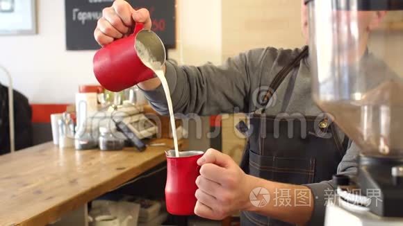 男咖啡师的特写镜头将牛奶倒入杯中，准备拿铁