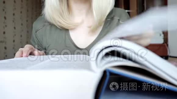 模糊而不可辨认的金发女人翻阅着一本大书-学习和教育概念