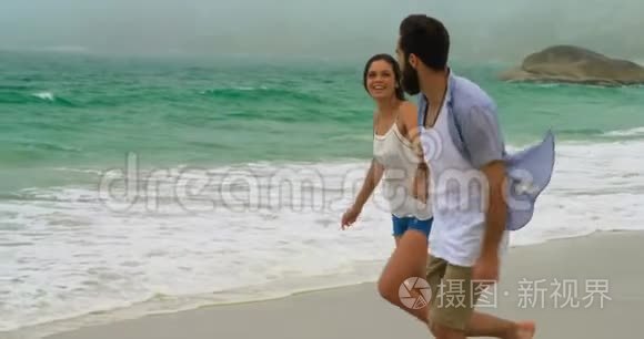 白种人夫妇手牵手在海滩上奔跑的侧面景色