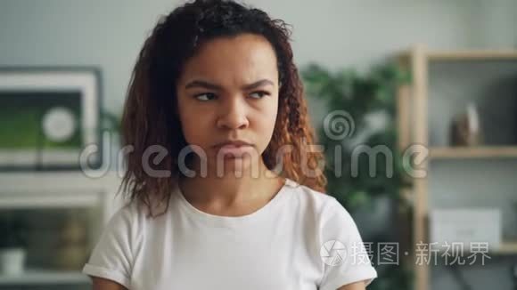 一幅疯狂而愤怒的非裔美国女孩站在家里，满脸不高兴，皱着眉头看着镜头的肖像