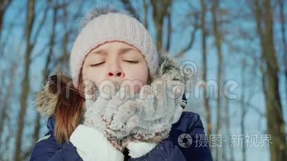 少女在冬天用针织手套吹雪花
