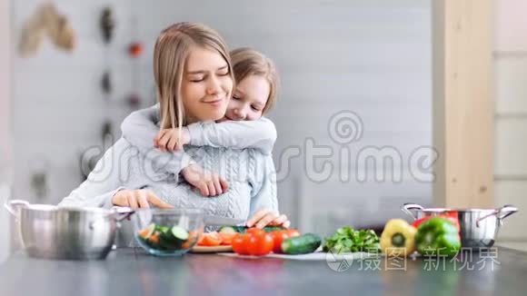一个可爱的女孩正在厨房里拥抱她年轻的母亲