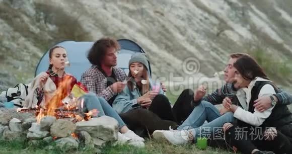 多文化的朋友一起旅行愉快，坐在篝火前，一起喝酒