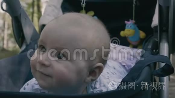 慢动作-婴儿车里的小男孩趴在肚子上微笑。