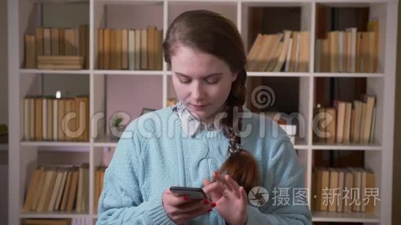 大学图书馆室内年轻漂亮女生用手机看镜头特写