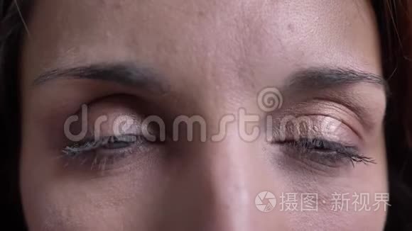 中年白种人女人在黑色背景下认真观看镜头的特写眼画像。