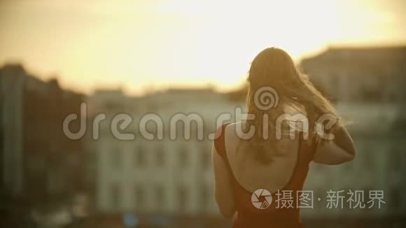 一个穿着红裙子的年轻女子站在屋顶上修头发——日落