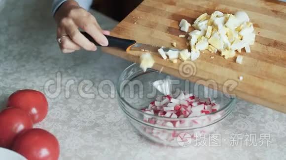 闭上女人的手，把切片的鸡蛋放在盘子里。 家庭主妇做季节性沙拉