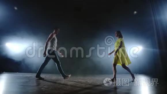 两名现代芭蕾舞演员正在舞台上用烟熏火燎的方式跳舞，一名男子举起他的舞伴，旋转进来