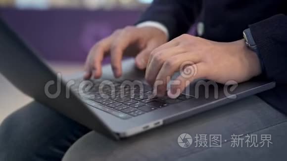 用智能手表在灰色笔记本电脑上打字，近距离拍摄男性手