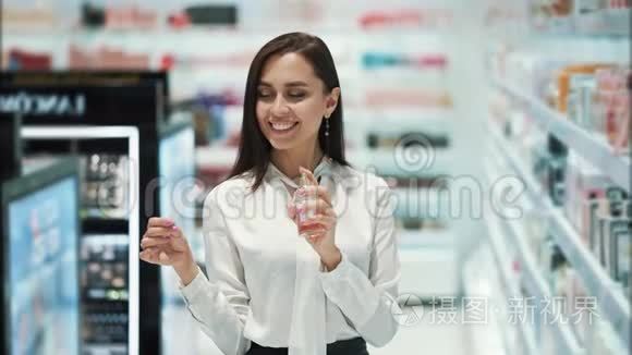 漂亮的女孩在化妆品店里选择香水，喷在测试器上，嗅嗅
