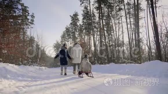 带着孩子的女人走在穿过森林的雪道上