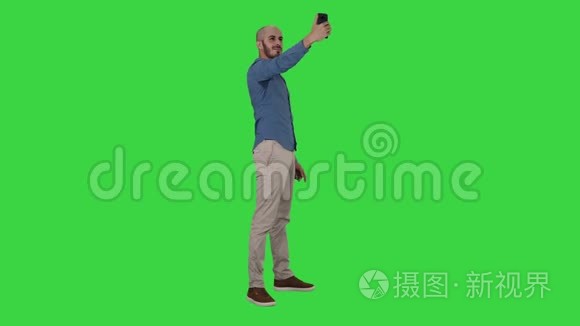 自拍时间！ 英俊的年轻人用手机在绿色屏幕上自拍，Chroma键。