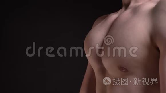 男性乳房轮廓的肖像，在黑色背景下移动和显示肌肉进入相机。