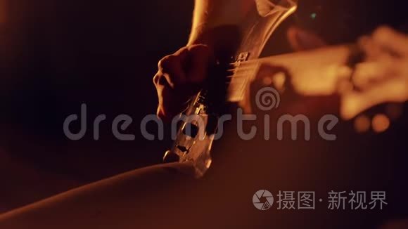 人类的手在电吉他上演奏。 在舞台上演奏吉他的摇滚乐手，在风景优美的灯光下