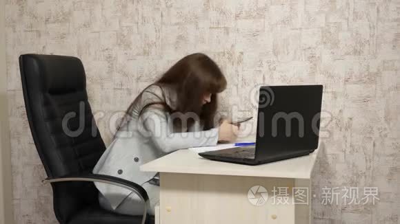 办公室里的女人在工作场所打哈欠。 疲惫的女孩想在工作时睡在桌子上。 女商人是