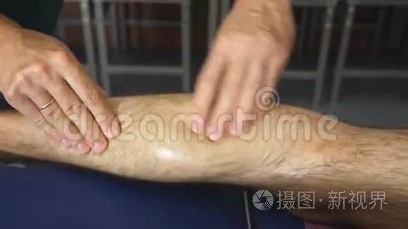 男手专业按摩师愈合按摩脚的年轻运动员与油在客厅。 一把大法师的