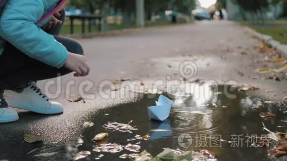 可爱的女孩在秋天公园的水坑里玩纸船。 童梦和旅行理念，生活方式..