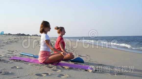 年轻女性在日落时坐在平静的海滩上的莲花姿势练习瑜伽。