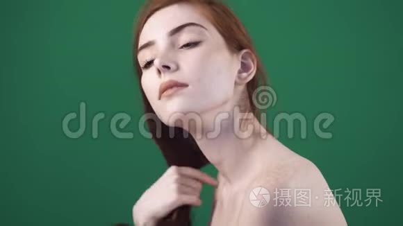 年轻的红发女人在镜头前摆姿势。 看头发的尖端。