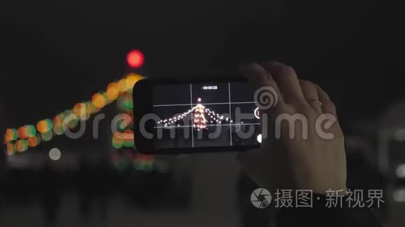一个女人在智能手机上燃放烟花。 用智能手机制作美丽烟花的视频，供庆祝。