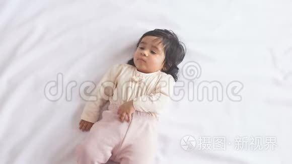 可爱可爱的非洲女婴躺在舒适的床上看着摄像机