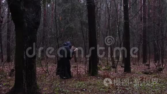 一个穿着黑色长袍的和尚带着一个杖穿过森林，一个穿着的游荡的德鲁伊穿过丛林。