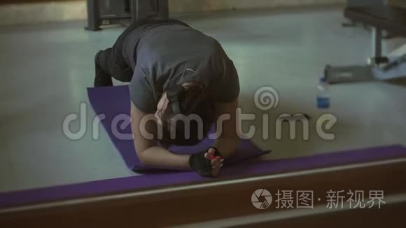 年轻的黑发女人在健身房锻炼木板