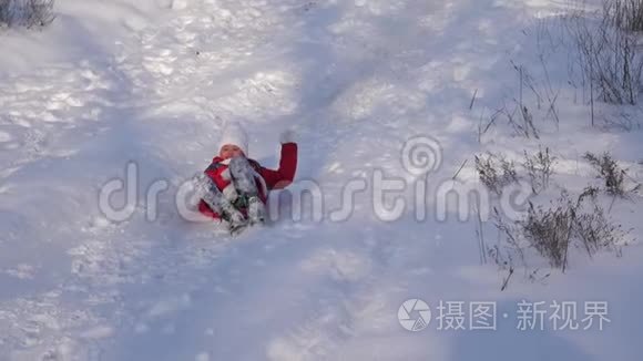 快乐的女孩骑着雪橇从高雪滑梯和笑声。 冬天在圣诞公园休息的女孩。