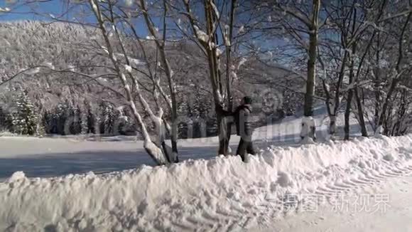 一个年轻人穿过雪山森林。 他从树上摇雪。 他很快乐，笑得很有趣。 慢动作