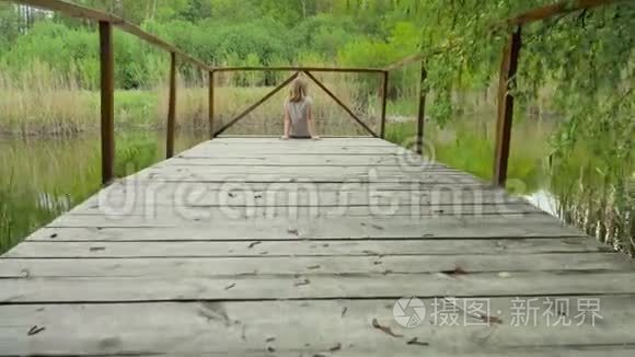 坐在河边的一座木桥上的少女