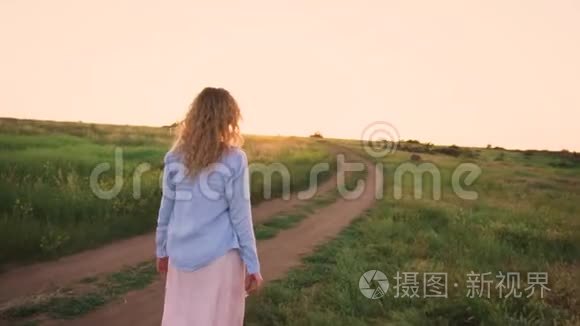 美丽的风景，绿色的田野，明亮的天空，纤细的金发女孩在漫长的松散的道路上行走