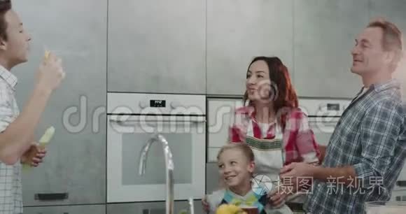 爸爸和妈妈和他们的两个儿子在一个现代化的厨房里玩有趣的泡泡一天。
