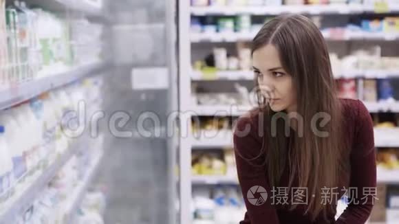 在购物中心食品杂货店的冰箱里挑选奶制品的女人。