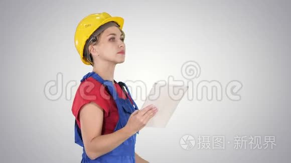 女建筑工程师在梯度背景上看平板电脑和检查对象。