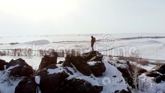 带着照相机的四架飞机飞过满是雪的山上，山上站着一个抱着胳膊的登山者