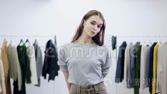 年轻漂亮的女人从某人身上拿出一件毛衣，并在服装室里摆姿势