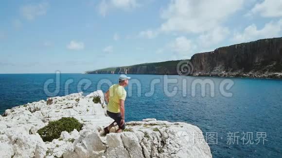 成就概念。迷人的男人胜利地举起手臂。男游客跳上悬崖庆祝