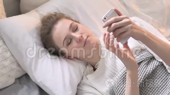 在床上使用智能手机的年轻女性的俯视图