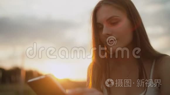 在公园里看电子书的年轻女子，夕阳西下