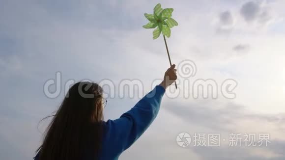 女孩在天空的背景下手握着风车