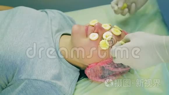 一位戴手套的男性美容师的手从女人的脸上摘下一根香蕉碎片