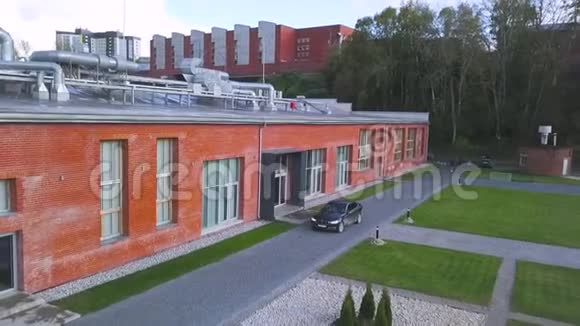 典型的红砖建筑黑色现代客车停在入口处附近艺术单层住宅的航空视频的预览图