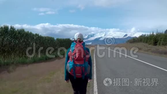 带背包的女旅行者在柏油路上视频