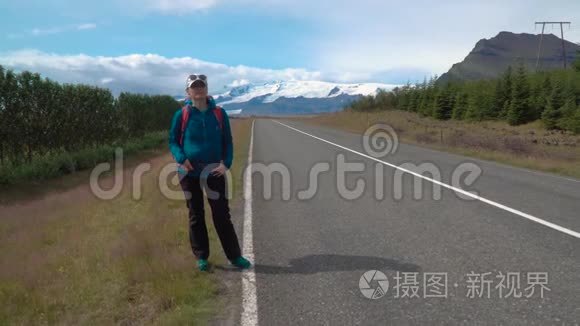 带背包的女旅行者在柏油路上视频