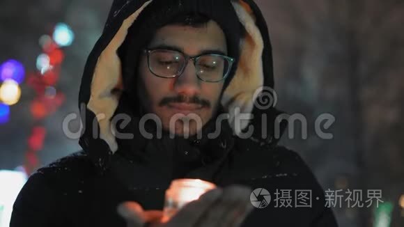 特写镜头，戴眼镜的印度男人沉思地看着手里拿着一支燃烧的蜡烛