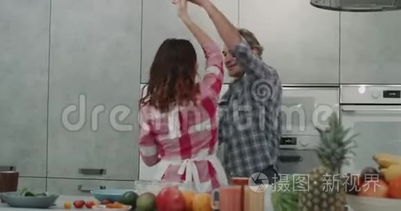 现代灰色厨房有魅力的夫妇在准备食物的时候在顾客面前跳舞。