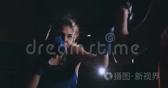 中等镜头的美丽健身女子拳击手treneruemsya打击速度焦点手套与教练在拳击俱乐部。 慢慢慢慢