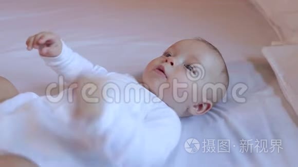 一个穿着白色衣服的可爱新生婴儿躺在卧室的床上。