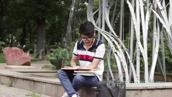 坐在喷泉附近学习的男学生视频